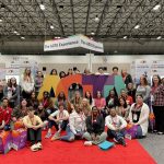 a group of students gathered around a sign that says "AOTA" in a convention center