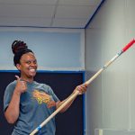 a woman giving a thumbs up while painting a wall