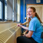 a woman painting a radiator vent