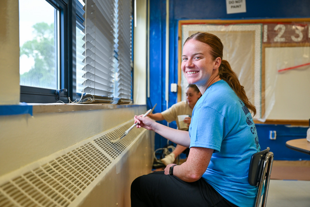 a woman painting a radiator vent